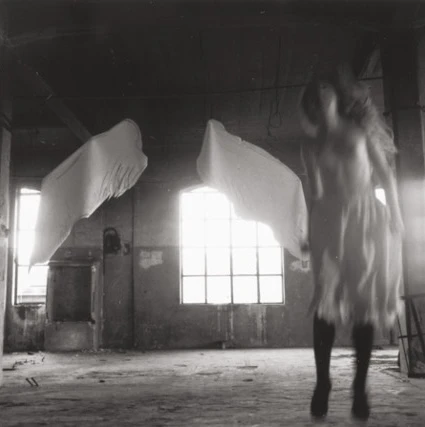 Black-and-white photograph of strange suspended figures in an abandoned room