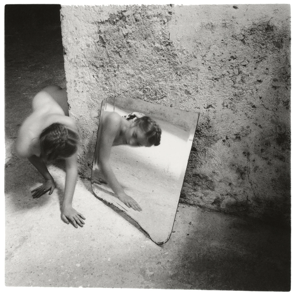 Black-and-white Francesca Woodman photograph of a woman beside a mirror