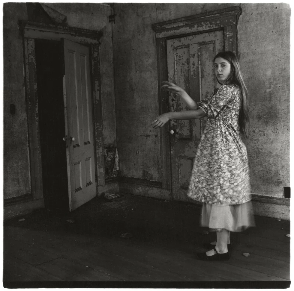 Black-and-white Francesca Woodman photograph of a girl in a weathered room
