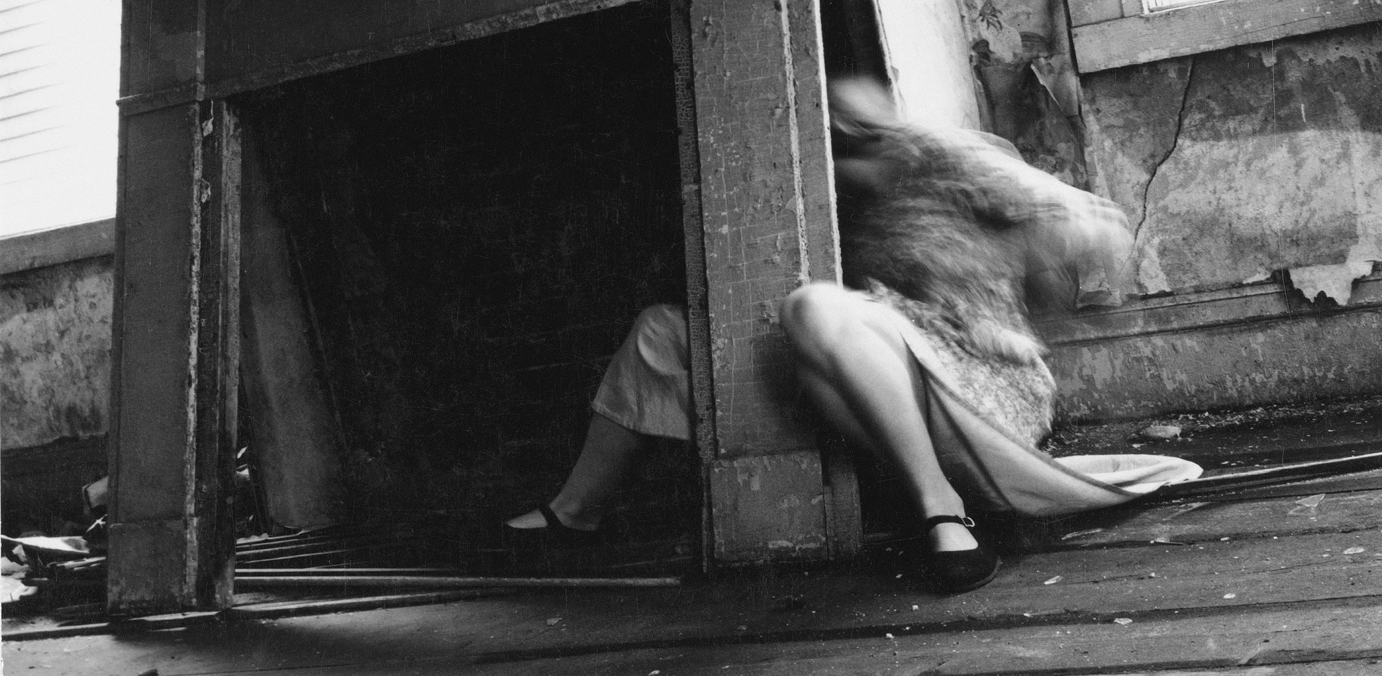 Black-and-white Francesca Woodman photograph of a blurred figure emerging from a cabinet