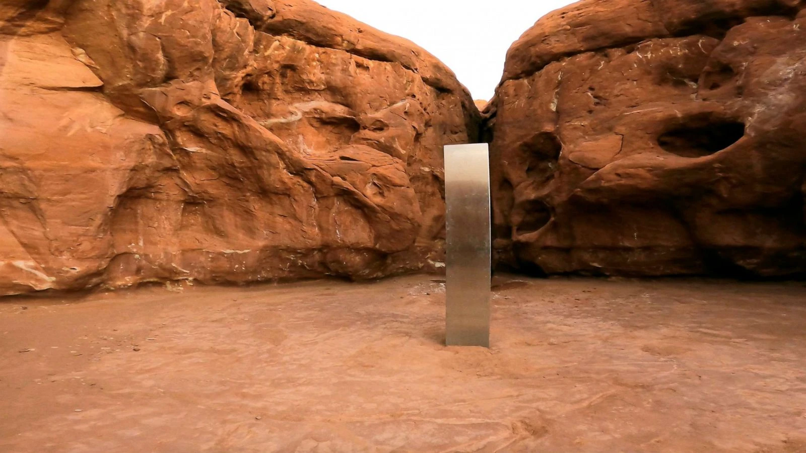 The Utah monolith standing between red rock walls